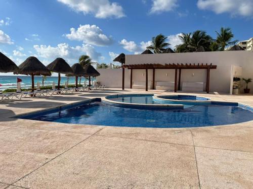 a resort pool with umbrellas and the ocean at Condominio Privado Villas Marlin Zona Hotelera Cancun in Cancún