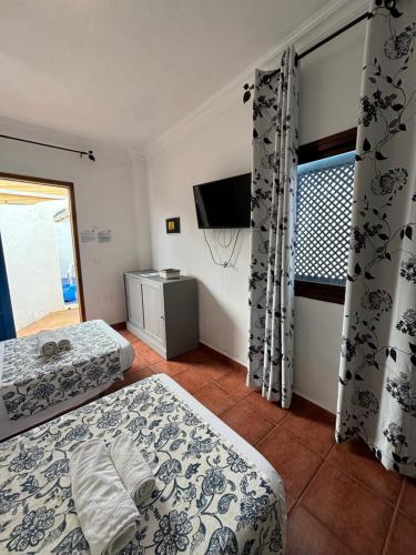 a bedroom with two beds and a tv and a window at Apartamentos y Habitaciones Villa Marina in La Caleta