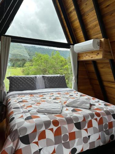 a bed in a room with a large window at Cabana Uruma in Urubici