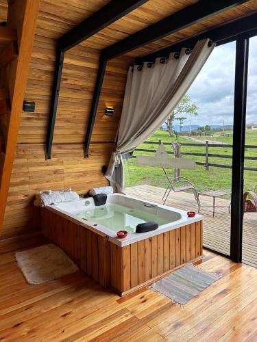 a hot tub in a room with a large window at Cabana Uruma in Urubici