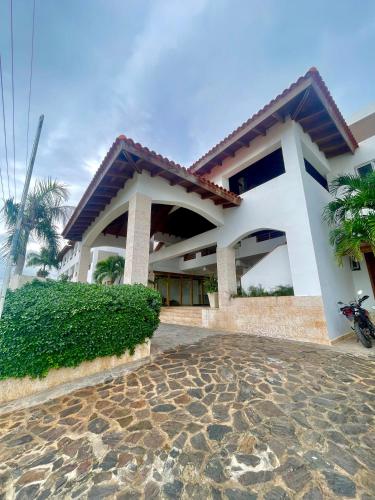 a white house with a motorcycle parked in front of it at Charming Bayahibe condo with pool and beach in Bayahibe