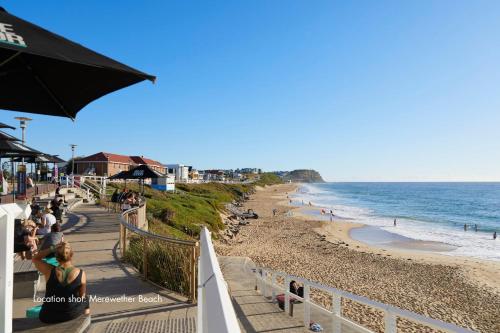 Una vista de una playa con gente y el océano. en The Breeze, en Merewether