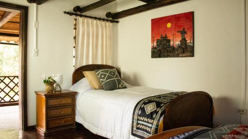 a bedroom with a bed and a dresser and a picture at Hacienda San Isidro Trails & Experiences in Cotacachi