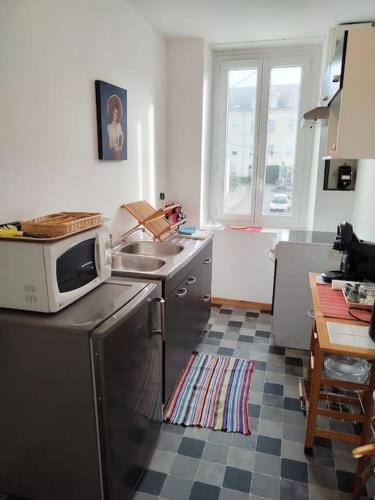 une cuisine avec un four micro-ondes au-dessus d'un comptoir dans l'établissement Duplex proche du centre-ville, à Decize