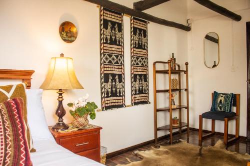 a bedroom with a bed and a lamp and a chair at Hacienda San Isidro Trails & Experiences in Cotacachi