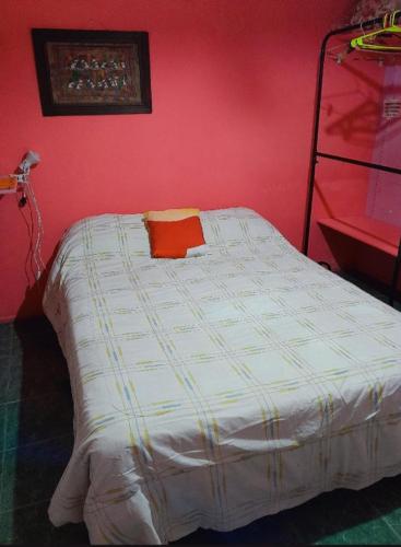 a bed in a room with a red wall at Aguaribay in Córdoba