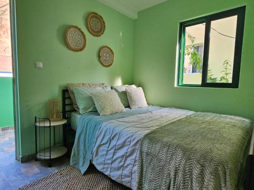 a green bedroom with a bed and a window at Casa Medina in Fajãzinha