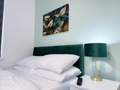 a white bed with a green headboard and a lamp at Portman Greens 3BR Entire Home in Middlesbrough