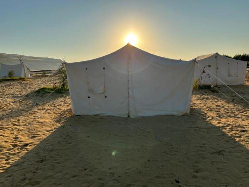 a tent on the beach with the sun in the background at Sun & Fun Camp Fayoum in Fayoum Center