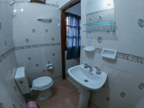 a white bathroom with a toilet and a sink at Imaynalla Humahuaca Hostl in Humahuaca