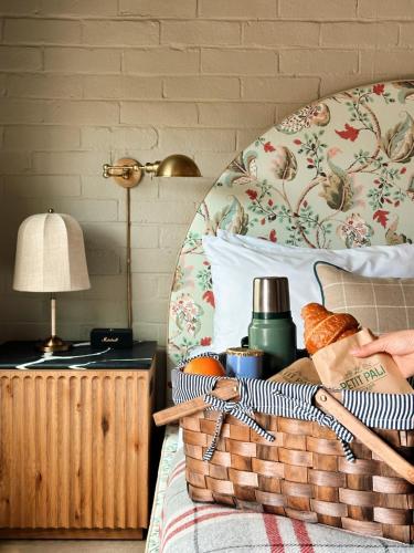 a bed with a basket and a lamp on a table at Le Petit Pali Brentwood in Los Angeles