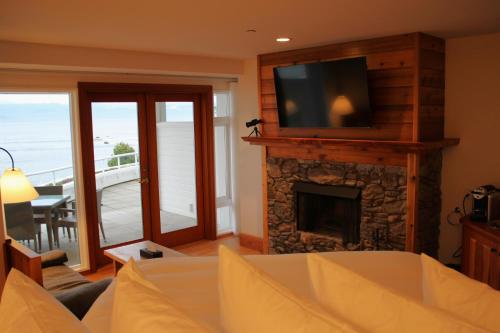 a living room with a fireplace with a flat screen tv at Sooke Harbour House in Sooke