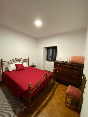 a bedroom with a red bed and a dresser at Casa da Avó Bia in Penhascoso