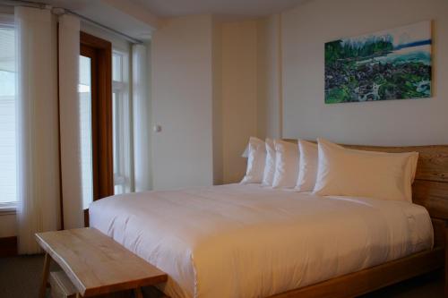 a bedroom with a white bed and a wooden table at Sooke Harbour House in Sooke