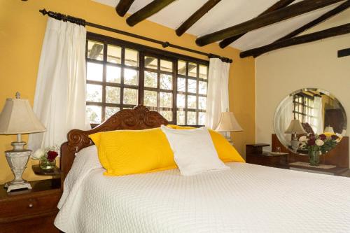 a bedroom with a bed with yellow and white pillows at Hacienda San Isidro Trails & Experiences in Cotacachi