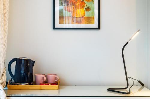 a table with a lamp and a picture on the wall at Modern Comfort En-Suite Room 2 in Oxford