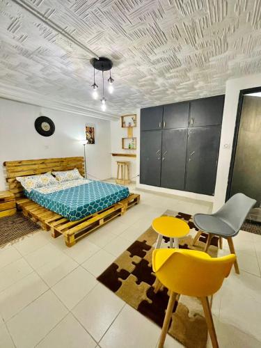 Un dormitorio con una cama y una silla amarilla. en Appartement Grace, en Abiyán