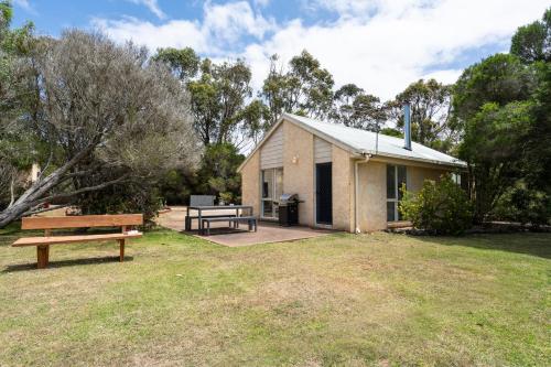 a small house with a picnic table and a bench at Bells Beach Cottages - Pet friendly cottage with wood heater in Torquay