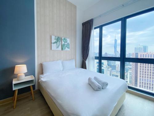 une chambre avec un lit blanc et une grande fenêtre dans l'établissement The Colony Infinitum By Happy Stay, à Kuala Lumpur
