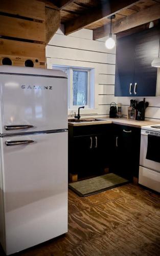 a kitchen with a white refrigerator and black cabinets at Le 10 - Spa Sauna Shower Bromont Lac-Brome in Bromont