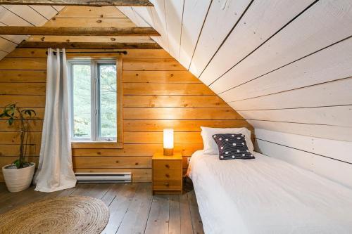 a bedroom with a bed in a log cabin at Le 10 - Spa Sauna Shower Bromont Lac-Brome in Bromont