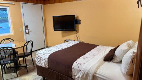 a bedroom with a bed and a flat screen tv at Apple Inn Motel in Chelan
