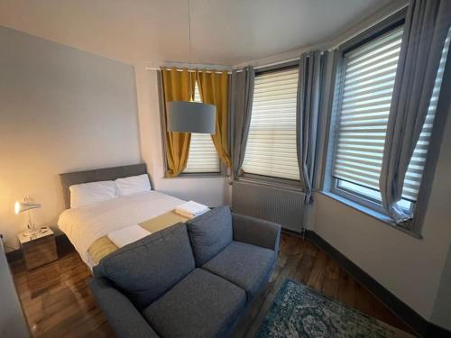 a bedroom with a bed and a couch and windows at 1 Large Comfy Garden Studio - Prime Location in Brighton & Hove