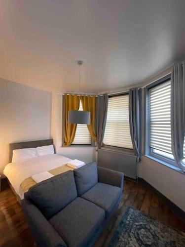 a bedroom with a bed and a couch and windows at 1 Large Comfy Garden Studio - Prime Location in Brighton & Hove