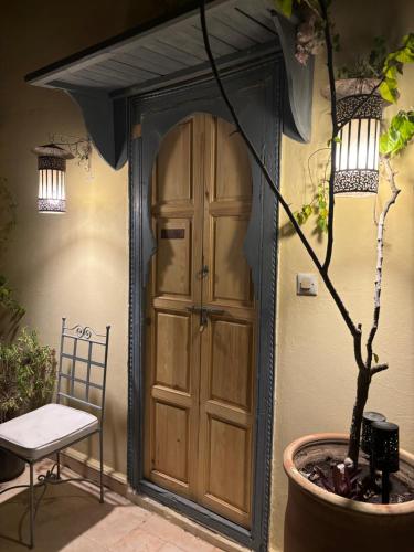 a porch with a door and a chair and a potted plant at RIAD DAR NAOMI in Marrakech