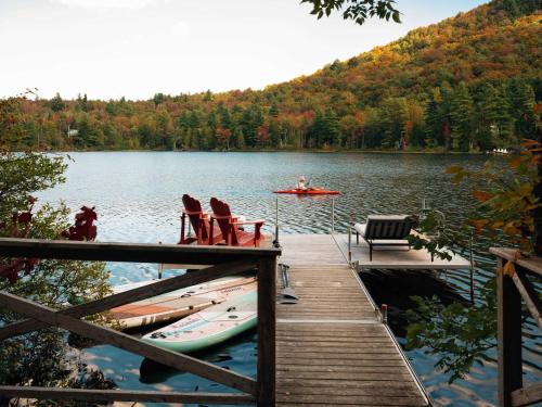 a dock with chairs and a boat on a lake at The Owl's Nest - Lakeside peacefulness ski & hiking in Austin