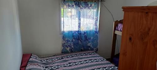 a bedroom with a bed with a curtain and a window at El nuevo amanecer mar de ajó in Mar de Ajó