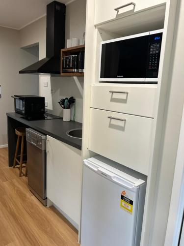 a white kitchen with a microwave and a refrigerator at Hunter Oasis in Morpeth