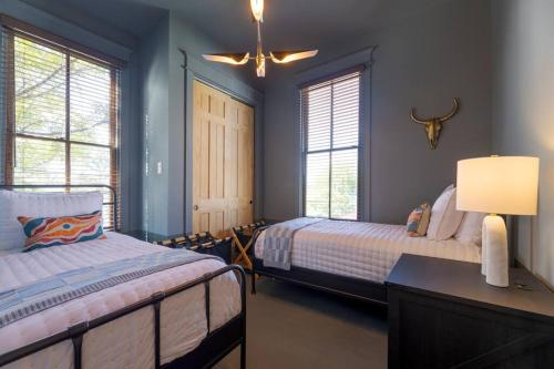 two beds in a room with blue walls and windows at Plum house in Galveston
