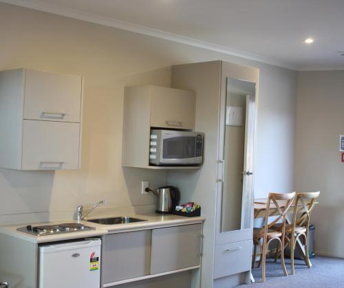 a kitchen with a sink and a microwave at Albert Court Motor Lodge in Hamilton