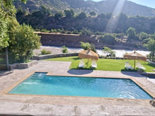a swimming pool with two umbrellas and two chairs at Altos de Guayacan in San José de Maipo