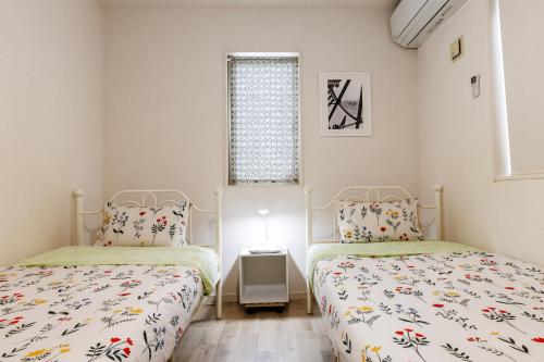 a bedroom with two beds and a window at 恩納村にあるMAXIMAOceanTerraceは1棟貸BBQ利用可能 in Onna