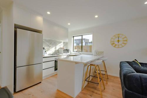 a white kitchen with a refrigerator and a counter at City Centre Elegance Apt 3 in Hamilton