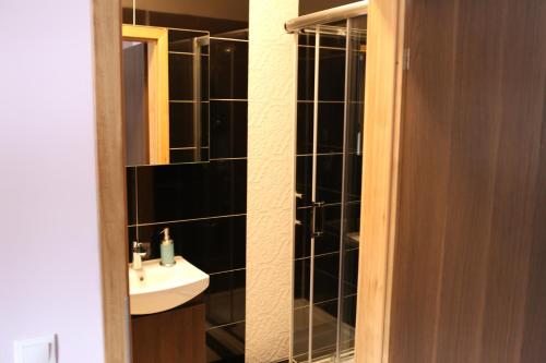 a bathroom with a sink and a black tiled wall at Noclegi Andersa in Wałbrzych