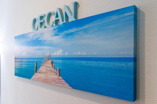 a painting of a pier in the ocean on a wall at 恩納村にあるMAXIMAOceanTerraceは1棟貸BBQ利用可能 in Onna