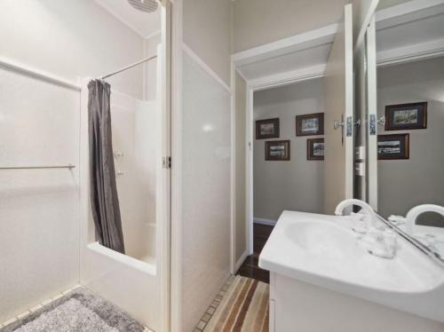 a white bathroom with a shower and a sink at Balgownie Cottage in Blackheath