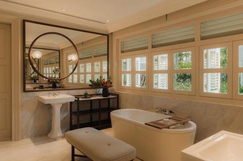 a bathroom with a tub and a sink and a mirror at Capella Singapore in Singapore