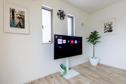 a living room with a flat screen tv on a white wall at 恩納村にあるMAXIMAOceanTerraceは1棟貸BBQ利用可能 in Onna