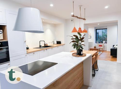 une cuisine avec des placards blancs et un comptoir blanc dans l'établissement Tranquiloue - Maison au charme d'Antan - PuyduFou, à Les Landes-Génusson