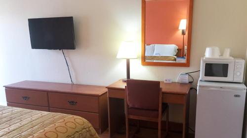 a hotel room with a bed and a desk with a microwave at Motel 6-San Diego, CA - Southbay in Chula Vista