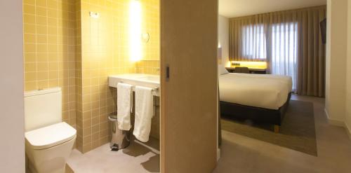 Habitación de hotel con baño con cama y aseo en Hotel A Pamplona, en Pamplona