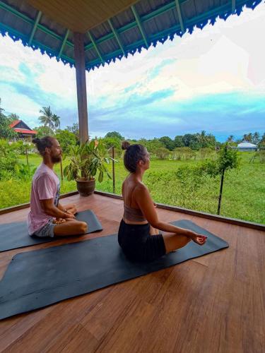 a man and a woman sitting in a yoga pose at Langkawi Country Lodge2 in Pantai Cenang