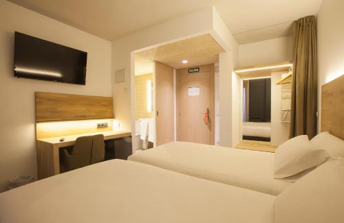 Una habitación de hotel con dos camas y un escritorio. en Hotel A Pamplona, en Pamplona