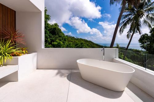 a white bath tub in a bathroom with a window at Anzhu Seamate Villa Samui in Amphoe Koh Samui