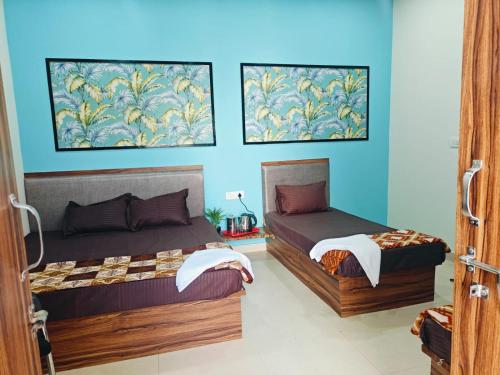 two beds in a room with blue walls at Hari Sharnam Home Stay in Mathura