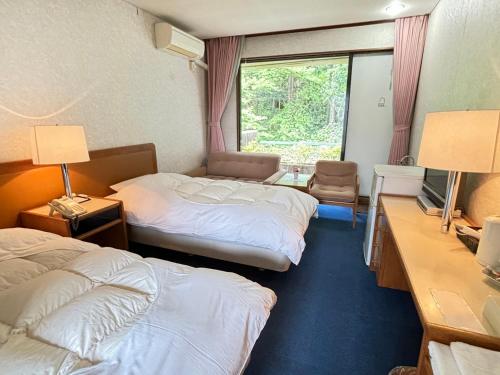 a hotel room with two beds and a window at Minami Hakone Villa in Kannami
